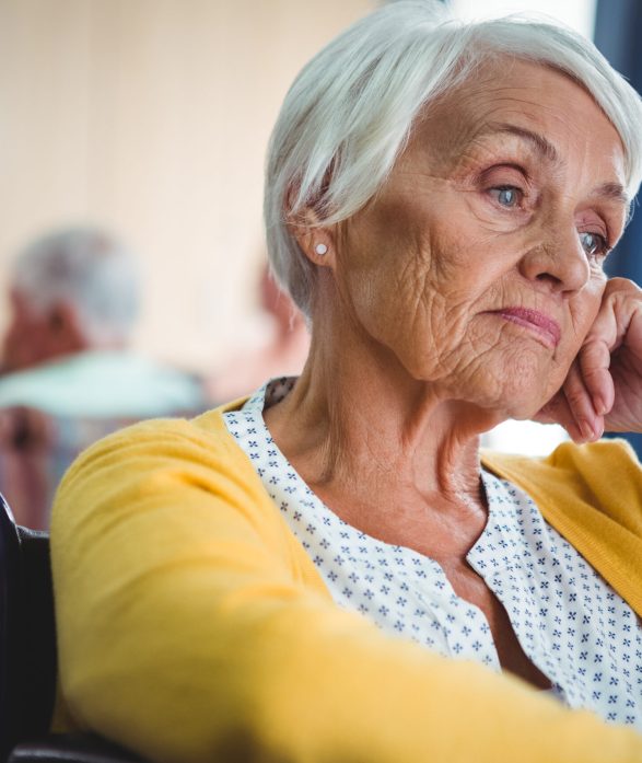 Senior woman in wheelchair look worried with hand holding her head